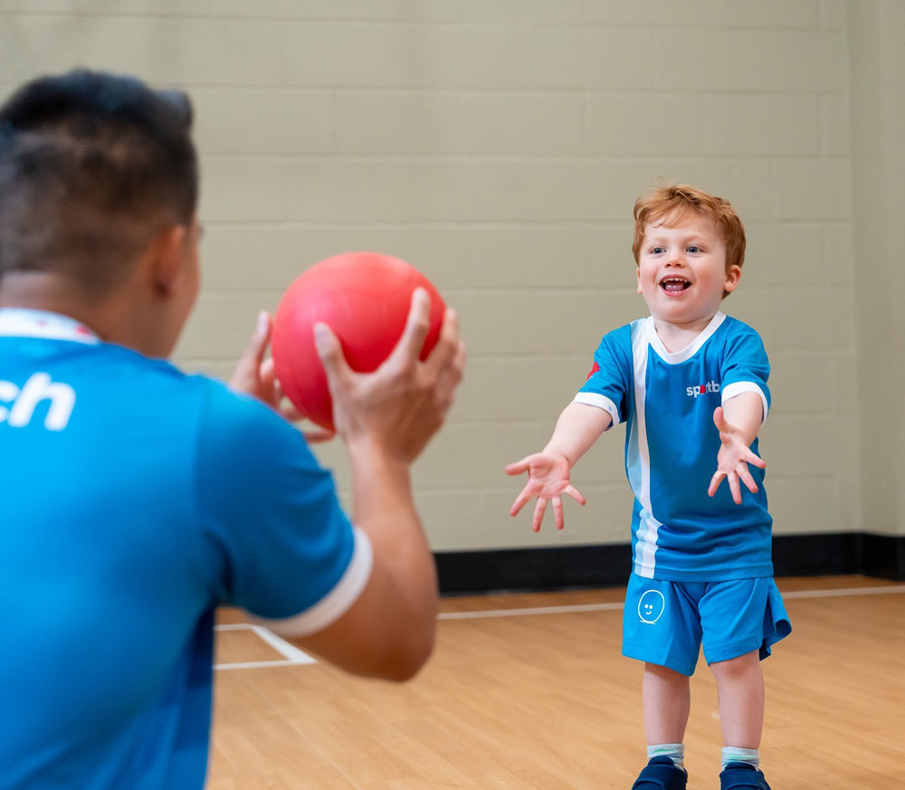 Boy catching ball from Sportball coach